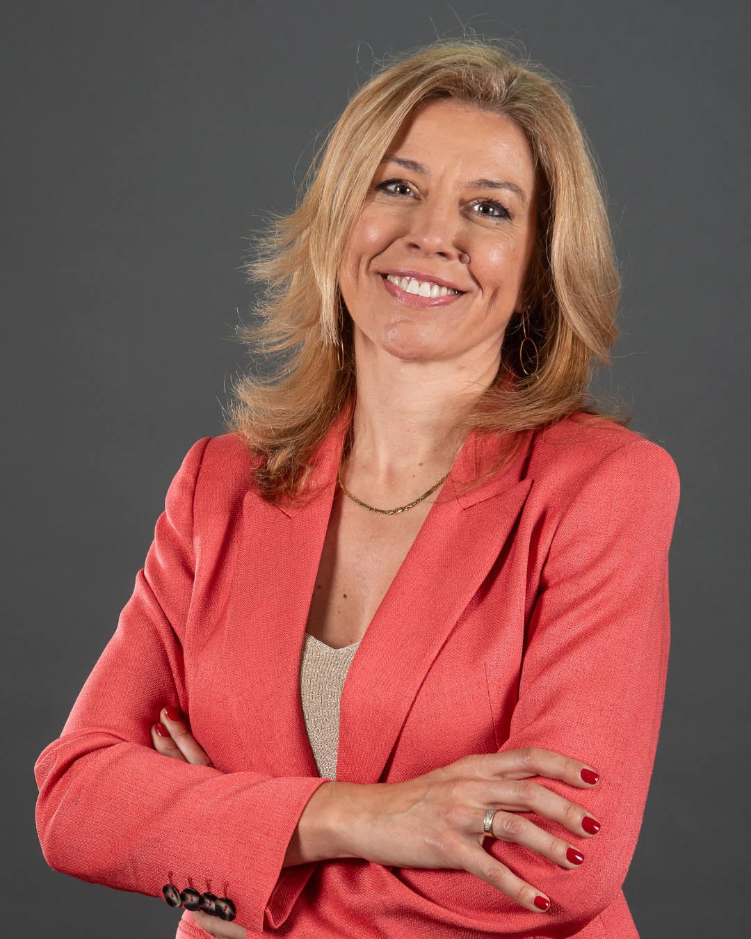 Mulher de blazer rosa posando confiante.